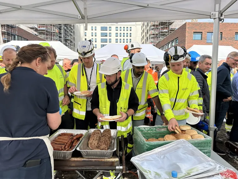 A group of people in safety vests standing around a table with food